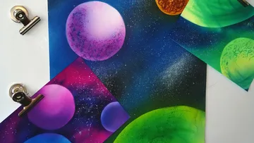 Bunte Planetenbilder liegen auf einem Tisch mit Klammern.