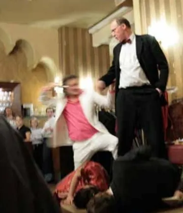 Zwei Männer kämpfen in einem Restaurant vor Publikum.