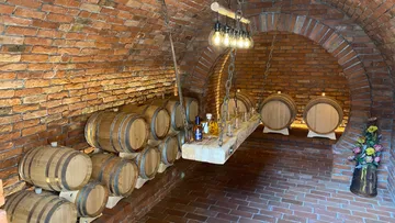 Fässer lagern, Flaschen stehen, Ziegelsteinwand im Weinkeller.