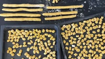 Pieces of dough lie on a surface and are prepared.