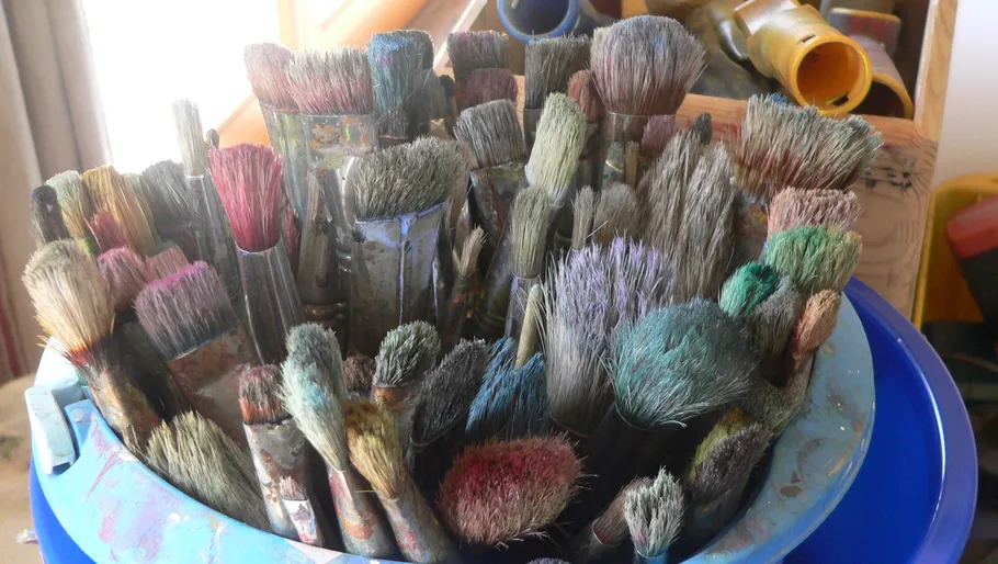 Eimer voller Pinsel, die in verschiedenen Farben stecken.