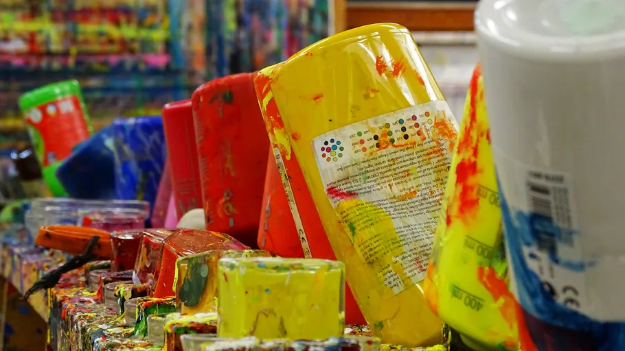 Colourful paint pots stand diagonally on a table.