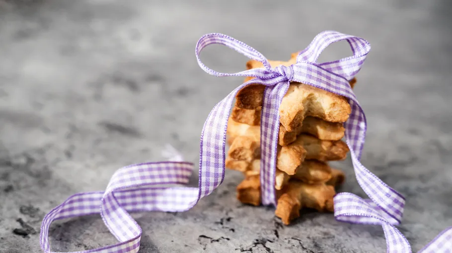 Stack of cookies with purple ribbon on gray background.