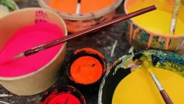 Paints and brushes lie chaotically on a table.