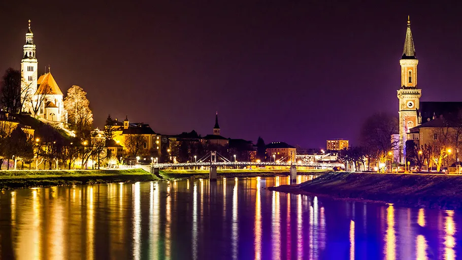 Lichter spiegeln sich im Fluss unter nächtlichem Himmel.