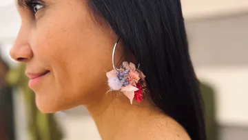 Große Ohrringe mit bunten Blüten an einer Frau.