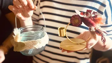 Glasbehälter und blumenverzierte Halter werden gehalten.