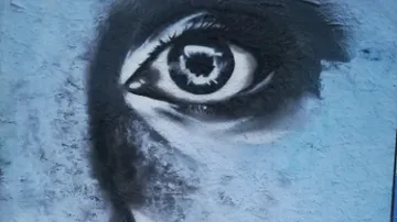 Graffiti of an eye on a blue wall.