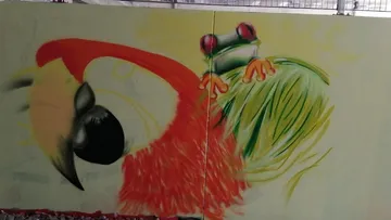 Buntes Graffiti zeigt einen Vogel mit einem Frosch.