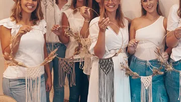 Fünf Frauen halten dekorative Kränze in einem Workshop.