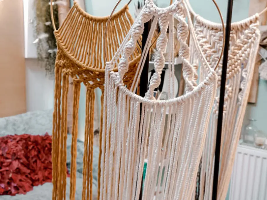 Macramé-Wandbehänge hängen nebeneinander in einem kreativen Studio.
