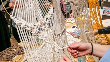 Macrame projects are made by several people around a table.