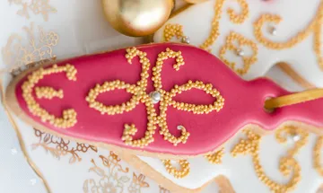 Red cookies with golden decorations on a festive background.