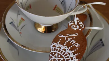 Gingerbread heart sits next to an elegant tea cup and saucer.
