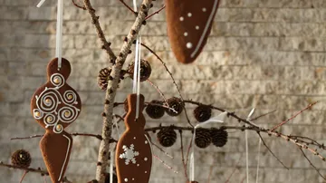 Gingerbread pendants hang from a branch with pine cones.