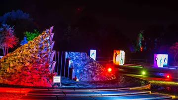 Colourful light installations illuminate stone structures at night.