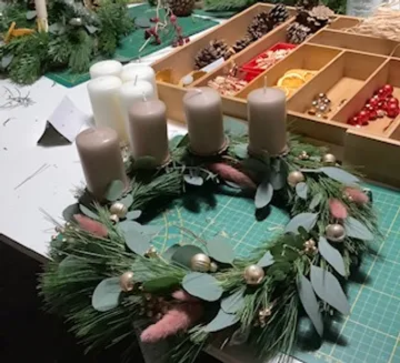 Ein Kranz mit vier Kerzen steht auf einem Tisch.