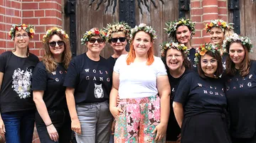 Gruppe von Frauen in Blumenkronen, die draußen lächeln.