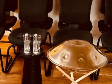 Handpan auf einem Tisch, neben Wasserflaschen, in einem Raum.