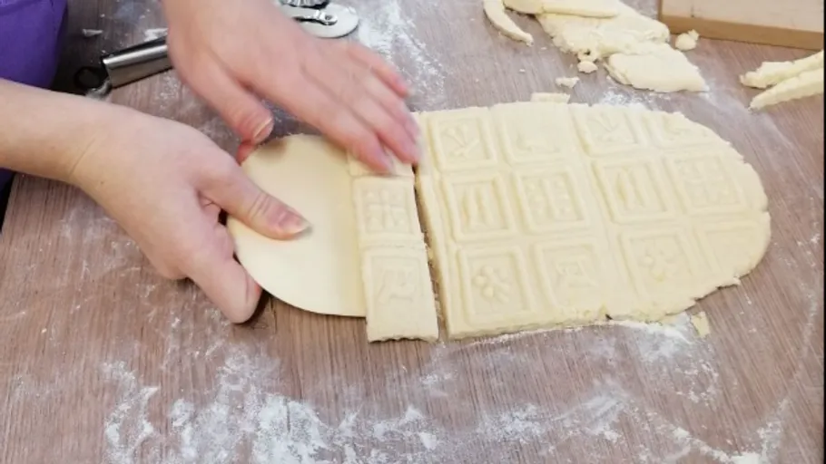 Mit den Händen Teig mit eingeprägten Mustern ausschneiden.