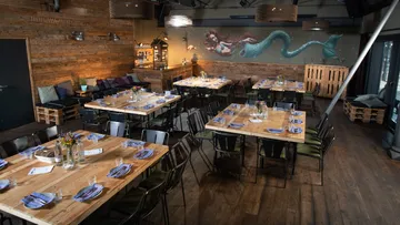 Wooden tables are set with wall art in a modern restaurant.