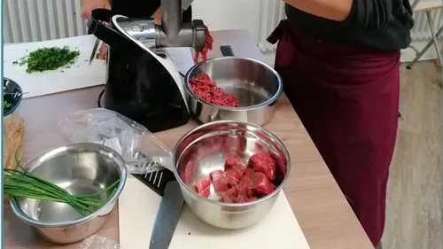 Fleischwolf mahlt Fleisch, während Zutaten vorbereitet werden.