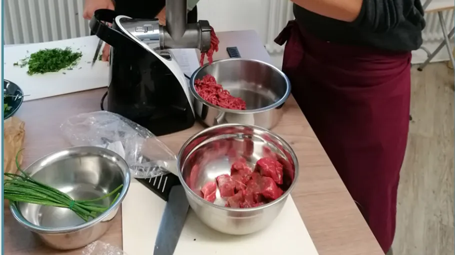 Fleischwolf mahlt Fleisch, während Zutaten vorbereitet werden.