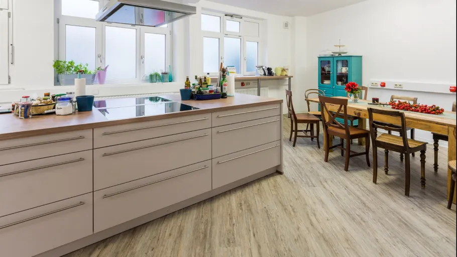Modern kitchen with cooking island, tables and window light.