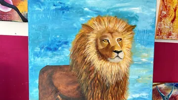 Löwe posiert majestätisch vor blauem Hintergrund in Kunstgalerie.