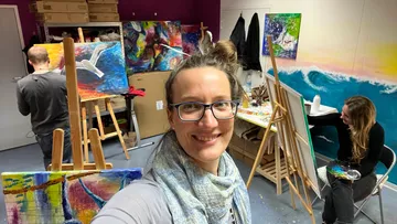 People painting in a creative studio with colorful pictures.