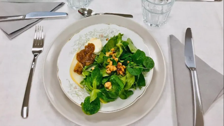 Teller mit Salat, Käse und Chutney auf dem Tisch.