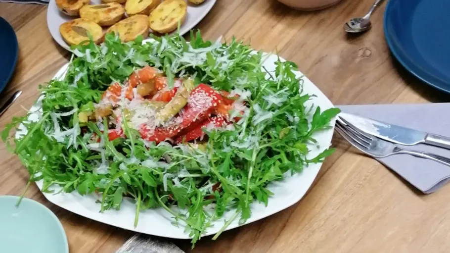 Ein Salat aus Rucola, Tomaten und Paprika auf einem Tisch.