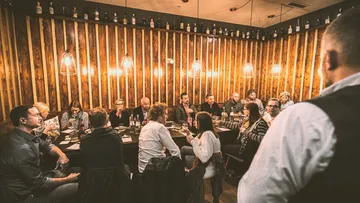 Group of people sit around a table in a restaurant.