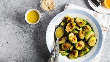Rosenkohl in einer Schüssel mit Sauce, auf einem Tisch.