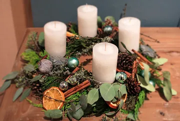 An advent wreath with white candles and decorations.