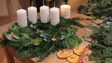 Weiße Kerzen stehen auf einem dekorierten Adventskranz.