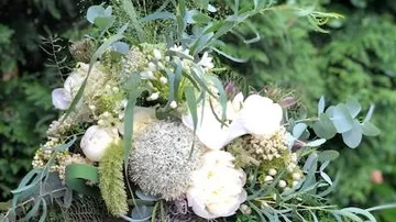 A bouquet of flowers is kept surrounded by green plants.