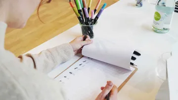 Stift schreibt in einem Notizbuch auf einem Tisch.