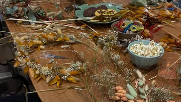 Blumenkränze und Snacks liegen auf einem Holztisch.