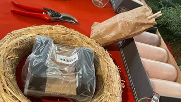 Strohkranz liegt auf rotem Tisch, Materialien für Dekoration.