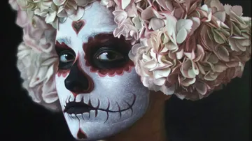 Person with skull makeup and flower bonnet looks intensely.