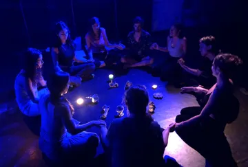 Group session in the dark, people meditating surrounded by candles.