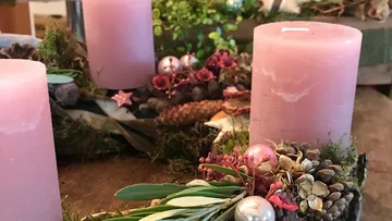 Rosa Kerzen stehen dekorativ in einem Naturkranz.