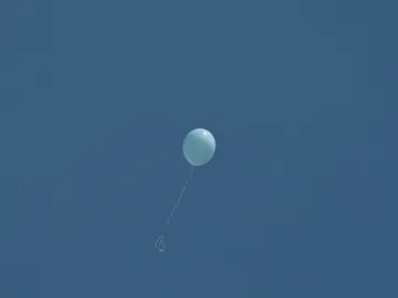 A blue balloon floats high in the clear sky.
