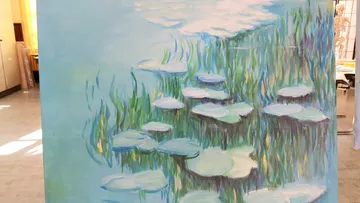 Water lilies float on water among green plants in the picture.