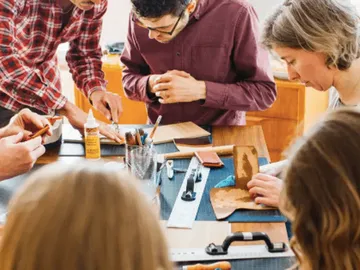 Group works together on leather craft project at the table.
