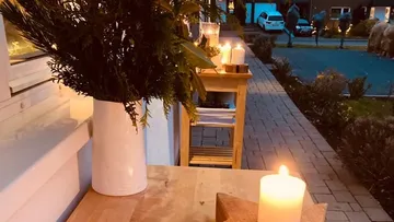 Vase with plants is on the table, candles are burning.