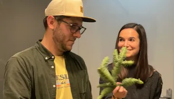 Man looks at a plant, woman smiles next to it.