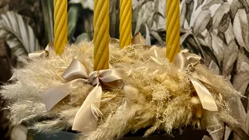 Yellow candles stand on a decorative, dried arrangement.