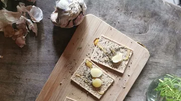 Brot auf Holzbrett mit Knoblauch und Kräutern dekoriert.